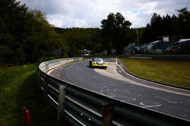 The yellow Porsche 911 GT3 with the starting number 91 from Reiter Engineering drives through a long curve on the Nordschleife of the Nürburgring Lukas Ertl Matthias Benndorf Maximilian Johannes Ertl Stefan Ertl Reiter Engineering The characteristic green vegetation of the Eifel and the typical crash barriers of the Nordschleife characterize the picture In the background you can see marshals in orange clothing and the spectator area Yellow Porsche 911 GT3 91 from Reiter Engineering on the Nordschleife Copyright: xspeedshotx