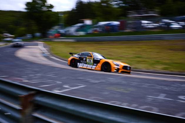 The orange-colored Mercedes AMG GT3 with the starting number 176 from PROsport Racing drives at high speed through a curve on the Nürburgring The vehicle Abée Anton Guilherme de Oliveira Jörg Viebahn LLuc Ibanez Yannik Himmels PROsport Racing clearly shows the sponsors NOVEM Gold and RAVENOL on the bodywork The panning shot emphasizes the dynamics of the racing car against the blurred background of the Nordschleife Mercedes AMG GT3 176 from PROsport Racing on the Nürburgring Copyright: xspeedshotx