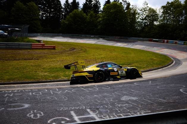 The Bastian Buss Michael Christensen Michael Klitgaard Christensen Dinamic GT from Dinamic GT drives through a tight right-hand bend on the Nürburgring The yellow and black car bears the starting number 54 and is branded with sponsors such as Pirelli, RAVENOL and DEKRA The typical Nürburgring backdrop with crash barriers, curbs and trees is visible in the background Porsche 911 GT3 54 from Dinamic GT in the bend at the Nürburgring Copyright: xspeedshotx
