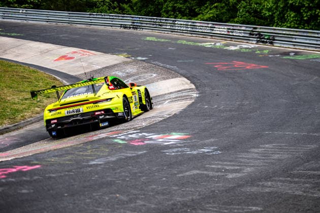 Manthey 911 SP 9 A yellow Porsche 911 GT3 R with sponsor stickers drives along a bend of the Nürburgring racetrack Rhineland-Palatinate Germany