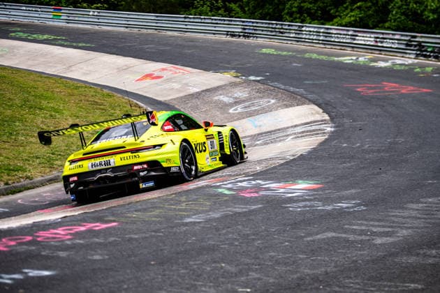 Manthey 911 SP 9 A yellow and green Porsche 911 GT3 R with advertising lettering drives along a bend of the Nürburgring Nordschleife Rhineland-Palatinate Germany