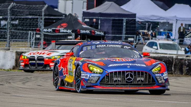 The Mercedes AMG GT3 with starting number 3 of the Mercedes AMG Team Verstappen Racing drives through the pit lane or a section of the Nürburgring track The car Daniel Juncadella Jules Gounon Lucas Auer Max Verstappen Mercedes AMG Team Verstappen Racing presents itself in the striking Red Bull livery in blue, Red and orange with prominent sponsors such as Red Bull, Viaplay, Gran Turismo and AMG A BMW from the ROWE RACING team can be seen in the background, while hospitality tents and spectators complete the backdrop of the 24h Nürburgring 2026 Mercedes AMG GT3 3 from Verstappen Racing at the Nürburgring Copyright: xMichaelxSchäferx