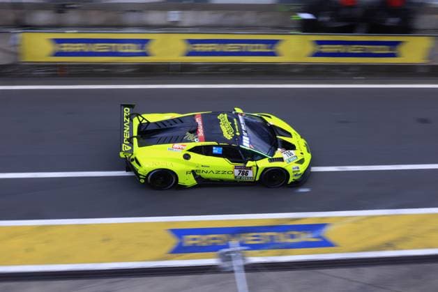 The striking neon yellow Lamborghini Huracán GT3 with the starting number 786 from Renazzo Motorsport drives through the pit lane at the Nürburgring The vehicle Christoph Breuer Dieter Schmidtmann Sak Nana Thomas Mutsch Renazzo Motorsport is decorated with the sponsors JOELA, WEMPE and RAVENOL and presents itself in a striking neon yellow and black design The RAVENOL track striping is clearly visible in the background Lamborghini 786 from Renazzo Motorsport in the pit lane Copyright: xspeedshotx