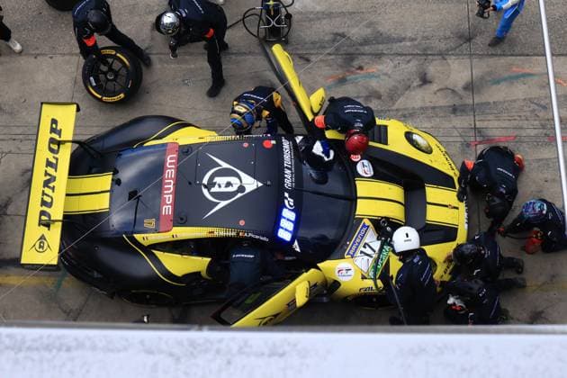 A birds eye view of Dunlop Motorsports Alessio Picariello Dorian Boccolacci Julien Andlauer Nico Menzel Dunlop Motorsport is seen during a pit stop at the Nürburgring The black and yellow car - with the Dunlop logo and sponsor Wempe prominently displayed on the hood - is attended to by several mechanics in dark overalls A driver change takes place, The drivers names J Andlauer, D Boccolacci, N Menzel and A Picariello can be read on the side of the car Dunlop Motorsport 17 at the pit stop at the Nürburgring Copyright: xspeedshotx
