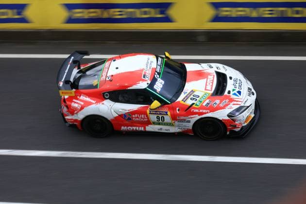 The Hugo Schwarze Javier Sagrera Toyota Racing United from Toyota Racing United drives through the pit lane at the Nürburgring The red and white car with the starting number 90 bears the sponsors MOTUL, eFUEL GROUP, RAVENOL and FALKEN and is equipped with a striking rear wing The RAVENOL banner can be seen in the background along the track barrier Ferrari GT3 90 from Toyota Racing United at the Nürburgring Copyright: xspeedshotx