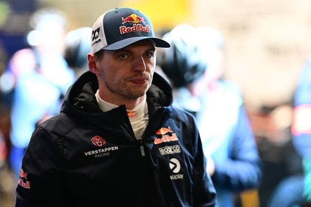 Max Verstappen from Mercedes AMG Team Verstappen Racing in the Nürburgring paddock He is wearing a dark blue team overall with Red Bull and Viaplay sponsors and a Red Bull cap Other people in team clothing can be seen in the background Max Verstappen in the paddock at the 24h Nürburgring 2026 Copyright: xMichaelxGelhardtx