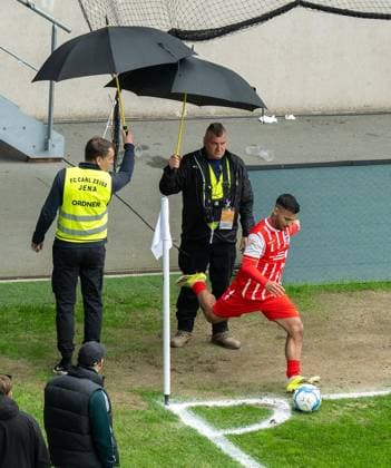 FOOTBALL REGIONAL LEAGUE NORTH-EAST 34 GAME DAY FC CARL ZEISS JENA FC ROT WEISS ERFURT FOR EDITORIAL PURPOSES ONLY p 16 05 2026 Jena Football Regionalliga Nordost 34 Matchday Season 2025 2026 Ernst Abbe Sportfeld FC Carl Zeiss Jena FC Rot Weiss Erfurt in photo Sejdo Durakov 54 FC RotWeiß Erfurt is protected by stewards with umbrellas at the corner kick Germany Thueringen Jena Copyright SaschaxFromm Copyright: SaschaxFromm doc85vo77rof784kxip1dgw ,EDITORIAL USE ONLY Copyright: SaschaxFromm