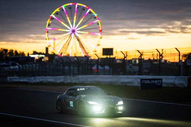 The Toyota GR Supra 524 TSV 1860 Mühldorf from SRS Team Sorg Rennsport drives at dusk on the Nürburgring The switched-on headlights shine brightly in the onset of darkness, while the illuminated Ferris wheel of the paddock shines in bright colors in the background The golden sunset gives the scene an atmospheric atmosphere A Falken Tyres banner can be seen on the track boundary Toyota GR Supra 524 at sunset at the Nürburgring Copyright: xMichaelxGelhardtx
