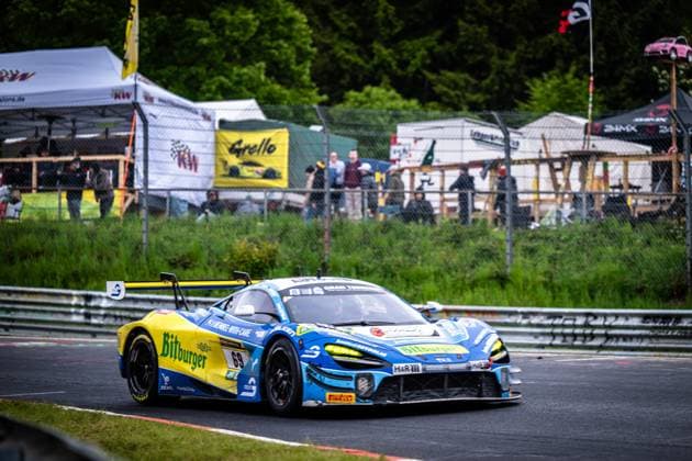 The McLaren GT3 with the starting number 69 from Doerr Motorsport drives through a curve on the Nürburgring The vehicle wears the striking yellow and blue Bitburger livery and is equipped with sponsors such as H R and Falken In the background, spectator areas and advertising banners from KW and Grello can be seen Ben Doerr Marvin Kirchhöfer Timo Glock Timo Scheider Doerr Motorsport McLaren GT3 69 from Doerr Motorsport on the Nürburgring Copyright: xMichaelxGelhardtx
