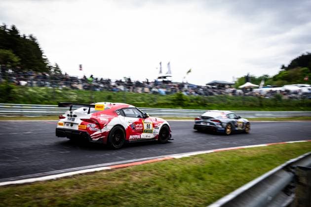 The Toyota GR Supra Hugo Schwarze Javier Sagrera Toyota Racing United of Toyota Racing United takes on an opponent in a fast corner at the Nürburgring The red and white vehicle with the sponsors eFuel Group and Motul is slightly offset and shows clear blurred movement, while another vehicle in gray and blue livery follows in the background The grandstands are filled with numerous spectators Toyota GR Supra 90 of Toyota Racing United in the duel at the Nürburgring Copyright: xMichaelxGelhardtx