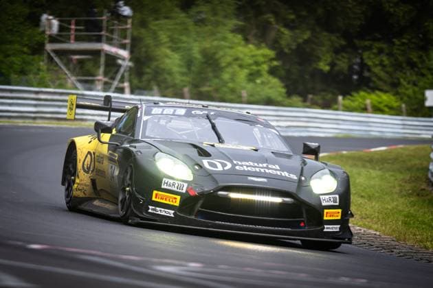 The Aston Martin Vantage GT3 Christian Krognes Mattia Drudi Nicki Thiim Felipe Fernandez Laser natural elements by Walkenhorst Motorsport from natural elements by Walkenhorst Motorsport drives through a tight bend on the Nordschleife of the Nürburgring The vehicle in characteristic dark green with yellow accents has the headlights switched on Sponsors such as natural elements, H R and RAVENOL as well as Pirelli logos are clearly visible In the background, crash barriers, a marshal tower and dense trees can be seen Aston Martin GT3 34 from natural elements by Walkenhorst Motorsport on the Nordschleife Copyright: xMichaelxGelhardtx