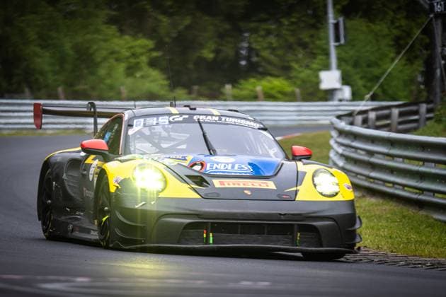 The Porsche 911 GT3 R Lukas Ertl Matthias Benndorf Maximilian Johannes Ertl Stefan Ertl Reiter Engineering from Reiter Engineering drives through a curve on the Nordschleife at the Nürburgring The vehicle in its characteristic black and yellow color scheme with a blue roof is on the road with illuminated headlights The sponsors Endless and Pirelli are clearly visible on the bodywork The typical crash barriers and the green vegetation of the Eifel can be seen in the background Porsche 911 GT3 R 91 from Reiter Engineering on the Nordschleife Copyright: xMichaelxGelhardtx