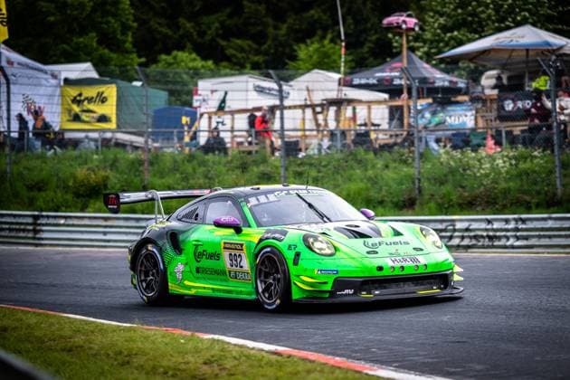 The Porsche 911 GT3 R Björn Griesemann Dirk Adorf Georg Griesemann Marco Holzer Manthey Team eFuel Griesemann from Manthey Team eFuel Griesemann drives through a bend on the Nordschleife of the Nürburgring The car wears the striking neon green livery with eFuels and RAVENOL sponsorship and is marked with the starting number 992 Spectators can be seen in the background, spectators, fan tents and the typical ambience of the 24-hour race can be seen Porsche 911 GT3 R 992 from Manthey Team eFuel Griesemann on the Nordschleife Copyright: xMichaelxGelhardtx
