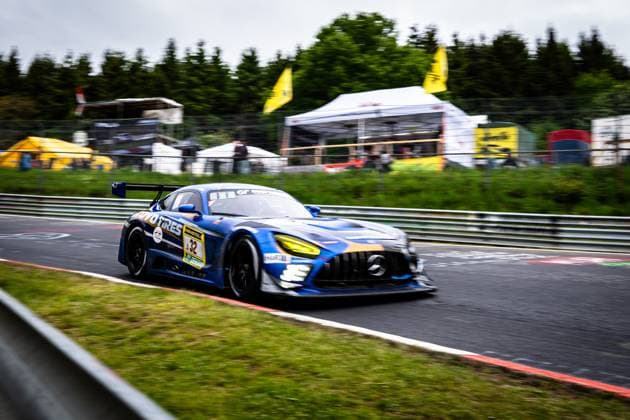 The Andreas Gülden Tim Sandtler Yuichi Nakayama Toyo Tires with Ring Racing Mercedes AMG GT3 from Toyo Tires with Ring Racing dynamically drives through a curve on the Nürburgring The blue and gold vehicle with the starting number 32 and striking yellow headlights is captured in slight motion blur, which emphasizes the high speed The spectator area and sponsor tents of the 24-hour race can be seen in the background Mercedes AMG GT3 32 from Toyo Tires with Ring Racing on the Nürburgring Copyright: xMichaelxGelhardtx
