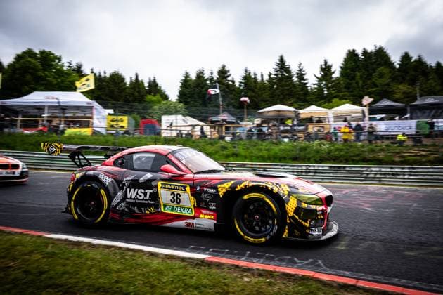 The BMW Z4 GT3 Christian Scherer Henry Walkenhorst Julian Reeh Ralf Schall Saugmotoren Motorsport 3M from Saugmotoren Motorsport 3M takes a corner on the Nordschleife of the Nürburgring The vehicle wears a striking black, red and yellow camouflage livery with the sponsors W S T Welding Specialists Team , RAVENOL, DEKRA and 3M Spectators, tents and trees can be seen in the background, the typical atmosphere of the 24h Nürburgring event BMW Z4 GT3 36 from Saugmotoren Motorsport 3M on the Nordschleife Copyright: xMichaelxGelhardtx