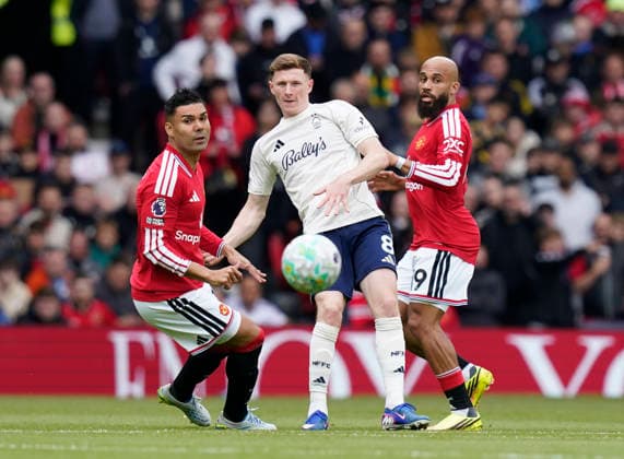 Manchester, England, 17th May 2026. Elliot Anderson of Nottingham Forest (c) plays between Casemiro of Manchester United, ManU (l) and Bryan Mbeumo of Manchester United (r) during the Manchester United vs Nottingham Forest Premier League match at Old Trafford, Manchester. Picture credit should read: Andrew Yates Sportimage EDITORIAL USE ONLY. No use with unauthorised audio, video, data, fixture lists, club league logos or live services. Online in-match use limited to 120 images, no video emulation. No use in betting, games or single club league player publications. SPI_042_AY_Man_Utd_Forest SPI-4806-0042