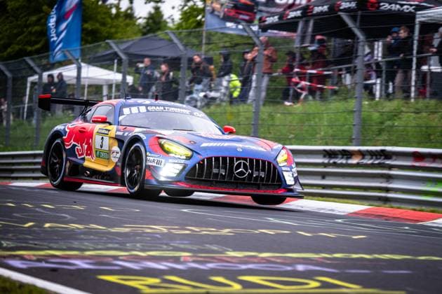 The Mercedes AMG GT3 of Mercedes AMG Team Verstappen Racing with the starting number Daniel Juncadella Jules Gounon Lucas Auer Max Verstappen Mercedes AMG Team Verstappen Racing takes a corner on the Nordschleife of the Nürburgring The vehicle wears the striking Red Bull livery in blue, Red and yellow with Gran Turismo and RAVENOL sponsorship The switched-on headlights and the aggressive downforce emphasize the high speed on the wet asphalt In the background, numerous spectators follow the race behind the crash barriers Mercedes AMG GT3 3 by Verstappen Racing on the Nordschleife Copyright: xMichaelxGelhardtx