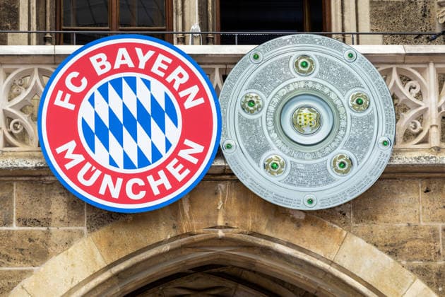 Fußball: Meisterfeier des FC Bayern München auf dem Rathausbalkon und am Marienplatz in München nach dem Gewinn der Bundesliga-Saison 2025 2026. Vereinslogo und Abbildung der Meisterschale am Rathausbalkon