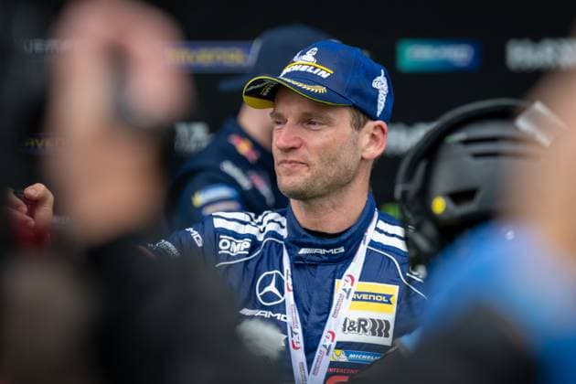 Maro Engel from Mercedes AMG Team RAVENOL stands in the paddock wearing the blue team kit with Mercedes AMG and RAVENOL sponsorship The driver of start number 80 is engrossed in conversation Maro Engel in the paddock of the 24h Nürburgring Copyright: xMichaelxGelhardtx