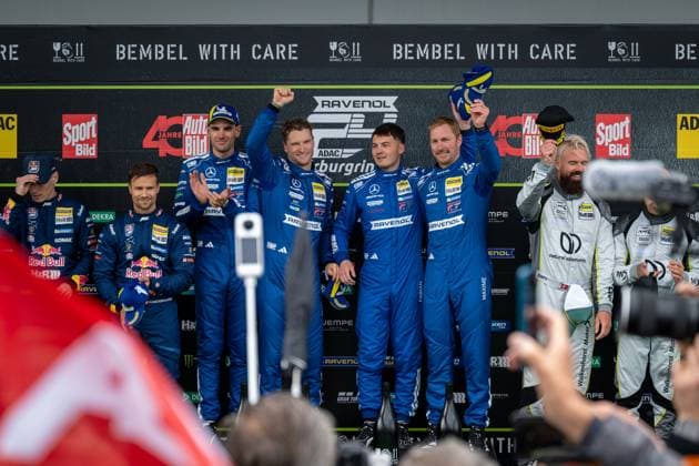 The drivers of Mercedes AMG Team RAVENOL present themselves on the podium after their victory in the 24-hour race at the Nürburgring The team in the characteristic blue racing suits with RAVENOL branding raises the trophy triumphantly in the air while spectators and photographers document the award ceremony Mercedes AMG Team RAVENOL 80 celebrates victory at 24h Nürburgring 2026 Copyright: xMichaelxGelhardtx
