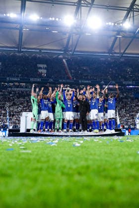 17 05 2026, Football, FC Schalke 04 Eintracht Braunschweig, Matchday 34, Bundesliga 2, Veltins Arena Gelsenkirchen, Season 2025 2026 Schalke 04 is champion of the 2 Bundesliga The team wins the championship and stands cheering on the pitch Joy and emotions after the victory Adil Aouchiche Schalke04 24 stands cheering with the championship trophy on the podium next to head coach Miron Muslic Schalke04 DFB regulations prohibit any use of photographs as image sequences and or quasi video North Rhine-Westphalia Germany