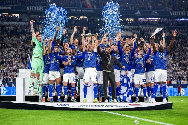 17 05 2026, Football, FC Schalke 04 Eintracht Braunschweig, Matchday 34, Bundesliga 2, Veltins Arena Gelsenkirchen, Season 2025 2026 Schalke 04 is champion of the 2 Bundesliga The team wins the championship and stands cheering on the pitch Joy and emotions after the victory Handover ceremony Kenan Karaman Schalke04 19 with the championship trophy in his hand next to head coach Miron Muslic Schalke04 on the podium DFB regulations prohibit any use of photographs as image sequences and or quasi video North Rhine-Westphalia Germany