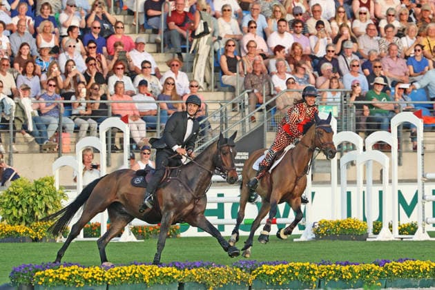 Richard Vogel and Luciana Diniz together in Bond Stunt Feeling over the obstacles, concert horse symphony, supporting program, motto of the evening James Bond, World Equestrian Festival, TSCHIO Aachen 2026, TSCHIO instead of CHIO 2026, Aachener Soers, 22 to 24 May 2026, equestrian sport, 23 05 2026, Aachener Soers Germany