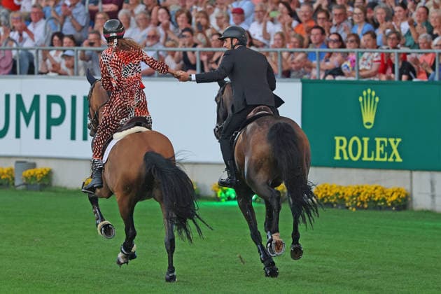 Richard Vogel and Luciana Diniz together in Bond Stunt Feeling over the obstacles, concert horse symphony, supporting program, motto of the evening James Bond, World Equestrian Festival, TSCHIO Aachen 2026, TSCHIO instead of CHIO 2026, Aachener Soers, 22 to 24 May 2026, equestrian sport, 23 05 2026, Aachener Soers Germany