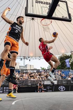 Exciting 3x3 basketball match at the FIBA 3x3 Hamburg Challenger on 23 May 2026 in the Active City Arena A player from Fuengirola red jersey with the number 6 starts a basket shot while a player from Amsterdam RABOBANK black jersey with orange leg sport tries to defend the action with a raised fist Fuengirola ESP vs Amsterdam RABOBANK NED - 3x3 Basketball in Hamburg Copyright: xspeedshotx