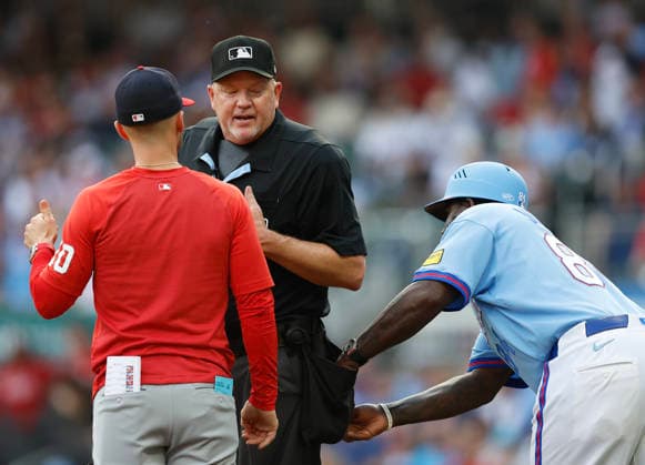Third base coach Tommy Watkins 84 of the Atlanta Braves tries to grab a baseball from the pocket of home plate umpire Ron Kulpa while Kulpa is arguing with Washington Nationals manager Blake Butera 10 during the game at Truist Park on Saturday, May 23, 2026 in Atlanta, Georgia.  ATL20260523121 MikexZarrilli