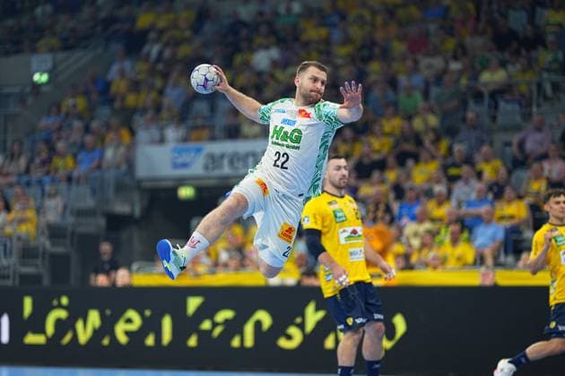 A player of SC Magdeburg 22, white jersey pulls up for a jump shot in the SAP Arena, while Jannik Kohlbacher 80, Rhein Neckar Löwen can be seen in the background The duel between Rhein Neckar Löwen and SC Magdeburg in the DAIKIN HBL makes for thrilling scenes in front of a sold-out crowd SC Magdeburg 22 in a jump shot against Rhein Neckar Löwen in the SAP Arena Copyright: xspeedshotx