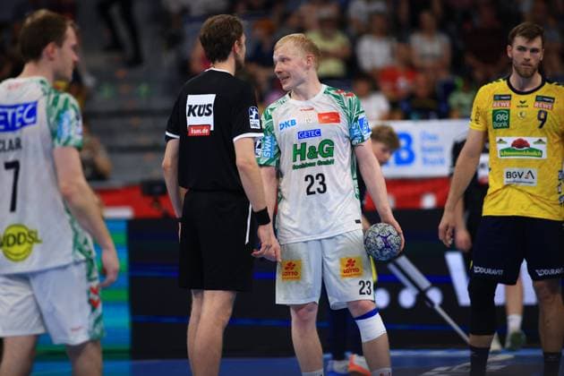 Magnus Saugstrup 23 SC Magdeburg stands with the ball in his hand and talks to a referee in the SAP Arena Felix Claar 7 SC Magdeburg and Steven Plucnar Jacobsen 9 Rhein Neckar Löwen can be seen in the background Magnus Saugstrup 23 SC Magdeburg talking to a referee Copyright: xspeedshotx