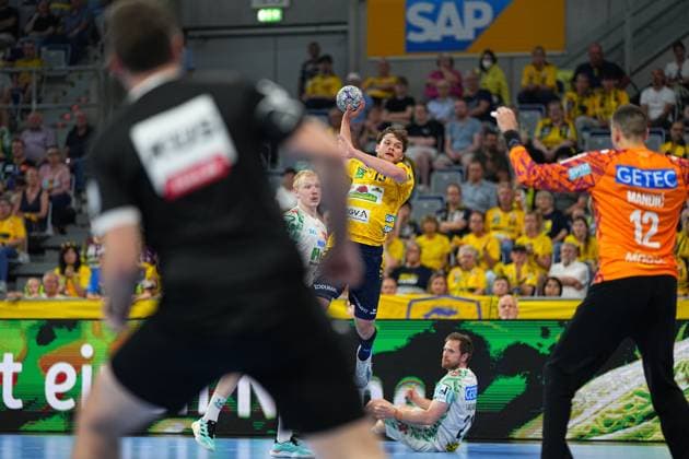 David Möré 15 Rhein Neckar Löwen jumps up in the SAP Arena and takes a shot on a counter-attack, while Magdeburg goalkeeper Matej Mandi 12 throws up his arms Magnus Saugstrup 23 SC Magdeburg tries to stop the attack in the background David Möré 15 Rhein Neckar Löwen taking a jump shot against SC Magdeburg Copyright: xspeedshotx