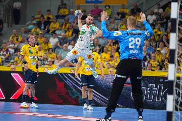 SC Magdeburg player Albin Lagergren 21 jumps with the ball in the throwing phase and aims at the goal, which is held by Rhein Neckar Löwen goalkeeper David Späth 29 In the background, Edwin Aspenbäck 78 observes the scene in front of the yellow-clad home fan curve in the SAP Arena Albin Lagergren 21 SC Magdeburg taking a jump shot against David Späth 29 Rhein Neckar Löwen Copyright: xspeedshotx