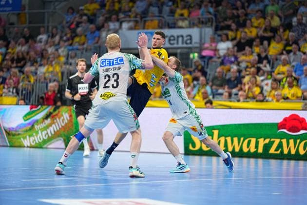 Sebastian Heymann 13 Rhein Neckar Löwen in yellow jersey penetrates the defense of Magnus Saugstrup 23 SC Magdeburg and another Magdeburg defender 14 The attacker jumps towards the goal and is tackled by both sides Sebastian Heymann 13 Rhein Neckar Löwen in a duel against SC Magdeburg Copyright: xspeedshotx
