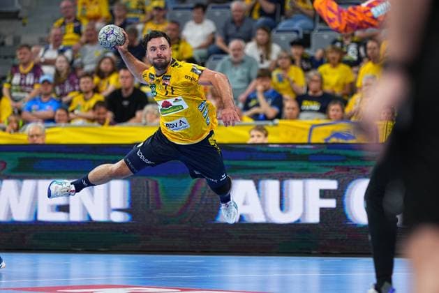 Dani Baijens 77 of the Rhein Neckar Löwen jumps off in his yellow jersey and takes a shot on goal In the background you can see the packed SAP Arena with numerous spectators Dani Baijens 77 Rhein Neckar Löwen attempting a shot in the SAP Arena Copyright: xspeedshotx