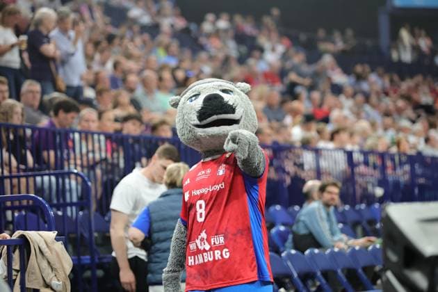 The HSV Hamburg mascot in a red jersey with the number 8 presents itself in the Barclays Arena in front of a packed crowd In the background you can see spectators and the equipment of the Bundesliga handball match HSV Hamburg mascot at Barclays Arena Handball Event Copyright: xspeedshotx
