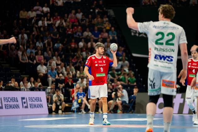 Jacob Lassen of HSV Hamburg holds the ball in his right hand during a move in the Barclays Arena In the background are players from Frisch Auf Göppingen in white jerseys, including Erik Persson 22 with raised hand Jacob Lassen 9 HSV Hamburg with ball in the Barclays Arena Copyright: xPhilippHeistx