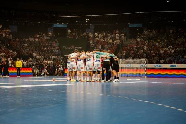 The Frisch Auf Göppingen team forms a closed circle on the pitch at Barclays Arena before the Bundesliga match against HSV Hamburg begins Spectators fill the arena in the background, while rainbow flags are visible on the boards Frisch Auf Göppingen team huddle in front of the Barclays Arena backdrop Copyright: xPhilippHeistx