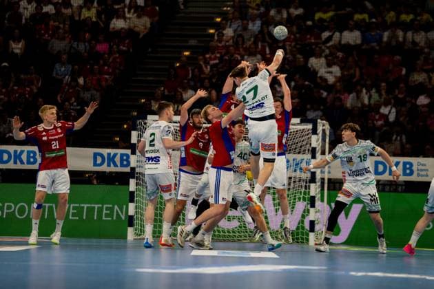 Frederik Bo Andersen jumps for the shot and throws the ball towards the goal while Frisch Auf Göppingen players form the defense The scene shows an intense attack by HSV Hamburg in the Barclays Arena with spectators in the background Handball Sport Verein Hamburg vs Frisch Auf Göppingen Copyright: xPhilippHeistx