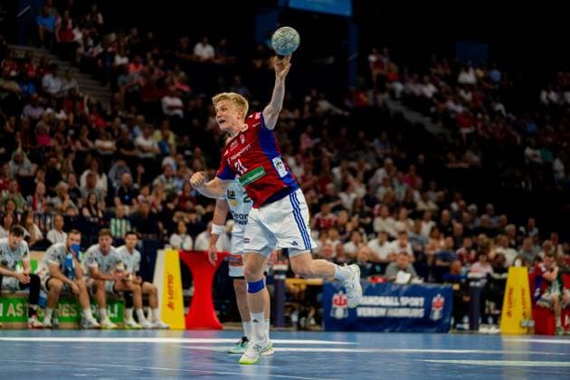 Frederik Bo Andersen throws the ball from the air with an outstretched arm towards the goal The HSV Hamburg player wears his red and blue home jersey and performs in front of a packed crowd in the Barclays Arena Handball Sport Verein Hamburg vs Frisch Auf Göppingen Copyright: xPhilippHeistx
