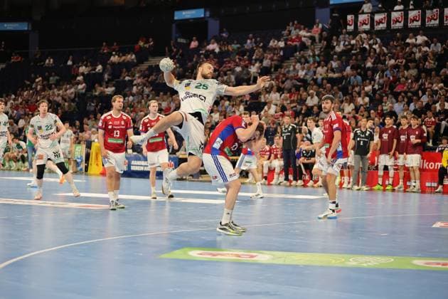Ludvig Jurmala Åström jumps to shoot and holds the ball above his head while Jacob Lassen 9 HSV Hamburg is in a defensive position underneath The game takes place in front of a full crowd at Barclays Arena Ludvig Jurmala Åström 25 Frisch Auf Göppingen taking a jump shot against HSV Hamburg Copyright: xspeedshotx