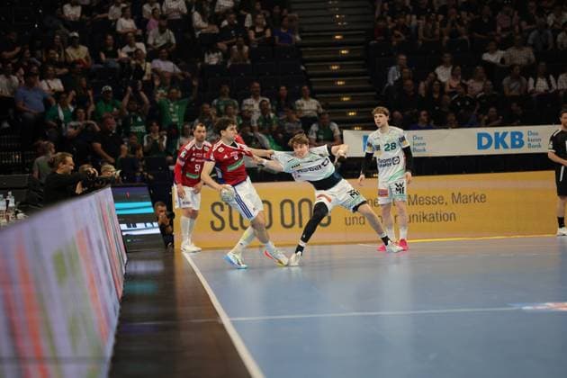 Torsten Jansen, head coach of HSV Hamburg, watches the action from the sidelines in the Barclays Arena A player in the red HSV jersey and defender from Frisch Auf Göppingen in the white jersey fight for the ball while the crowd watches the game Torsten Jansen watches the game scene at the DAIKIN HBL match Copyright: xspeedshotx