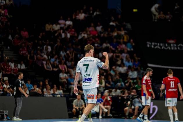 Victor Klöve wears the white jersey of Frisch Auf Göppingen and shows a cheering gesture during the match against HSV Hamburg In the background you can see HSV players in red jerseys and spectators in the Barclays Arena Handball Sport Verein Hamburg vs Frisch Auf Göppingen Copyright: xPhilippHeistx