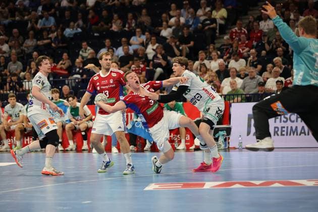 Erik Persson 22 Frisch Auf Göppingen in white jersey is fended off by Niklas Weller 13 HSV Hamburg and Moritz Sauter 33 HSV Hamburg in red jersey The scene shows an intense duel in the Barclays Arena with spectators in the background Erik Persson 22 Frisch Auf Göppingen in a duel against Niklas Weller and Moritz Sauter Copyright: xspeedshotx