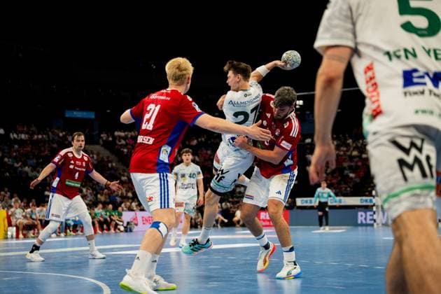 Players from Frisch Auf Göppingen white and HSV Hamburg red fight for the ball in the air during the Bundesliga match at the Barclays Arena The Göppingen player 27 tries to throw the ball over the defense while two Hamburg defensive players block the attack Handball Sport Verein Hamburg vs Frisch Auf Göppingen Copyright: xPhilippHeistx