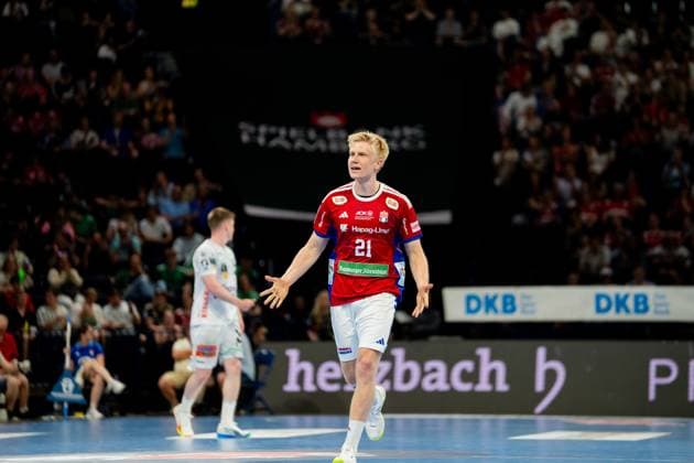 Frederik Bo Andersen runs across the pitch of the Barclays Arena with the ball in his hand A Frisch Auf Göppingen player in white jersey follows in the background Handball Sport Verein Hamburg vs Frisch Auf Göppingen Copyright: xPhilippHeistx