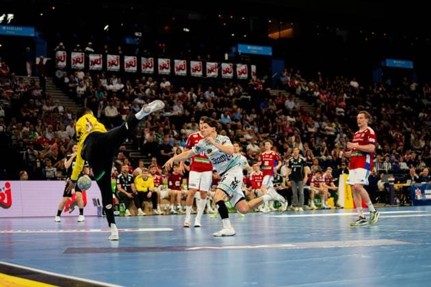 Moritz Sauter of HSV Hamburg in yellow jersey dribbles with the ball against the white-clad defense of Frisch Auf Göppingen A Göppingen player tries to interrupt the ball control while spectators in the Barclays Arena watch the intense game of the DAIKIN Handball Bundesliga Handball Sport Verein Hamburg vs Frisch Auf Göppingen Copyright: xPhilippHeistx