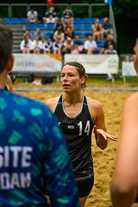 A player from the Dutch national team 14 NED stands on the sand court and talks to her teammates In the background, spectators can be seen on blue seats in the stands Dutch player 14 NED in conversation during beach handball Copyright: xspeedshotx xDorianfrickx