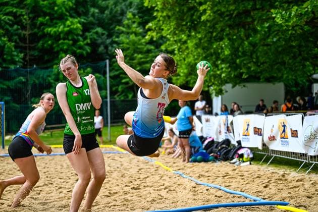A player in the blue jersey jumps and throws the ball towards the goal An opponent with the number 12 in the green DMV Group jersey watches the action of the throwing action at the beach handball tournament while jumping Copyright: xspeedshotx xDorianfrickx